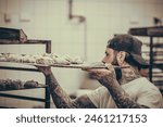 The baker pushes a tray of raw rolls of dough into a cart, vintage style with grain