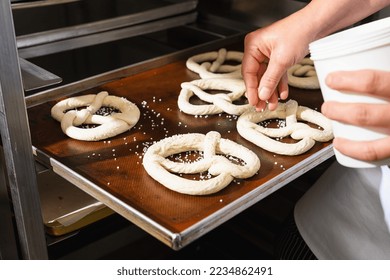 Baker salting raw pretzels on a baking sheet