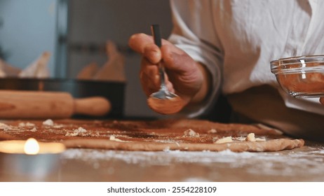 Baker speading butter and spices on rolled dough in a cozy, candle-lit kitchen - Powered by Shutterstock