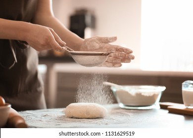 Baker sprinkling flour on dough at table - Powered by Shutterstock