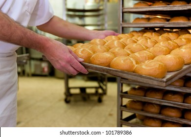 baker standing in his bakery in the morning and is baking bread or buns - Powered by Shutterstock