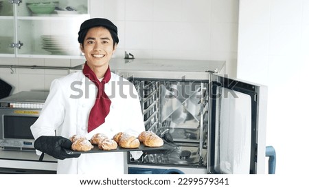 Baker taking bread out of the oven.