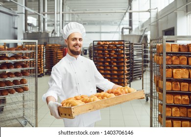 Baker in white uniform with trays of fresh bread costs in bakery. - Powered by Shutterstock