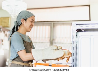 Baker Woman Taking Finished Cake Out Of The Oven