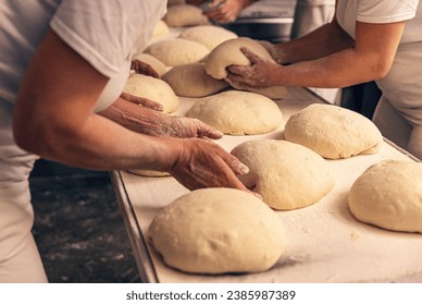 Bakers forming bread dough in a bakery. Bakery Concept. - Powered by Shutterstock