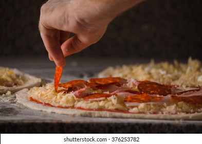 Baker-Hand, die Pizza mit Zutaten belegt