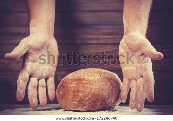 Baker\'s\
hands with a bread. Photo with high\
contrast