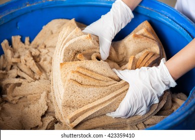 Baker's Hands Discarding Bread Waste In Garbage Bin