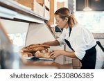 Bakery, busy and woman with bread in cafe for serving food, products and pastry for small business. Restaurant, coffee shop and person for service, help and baked goods for hospitality in store