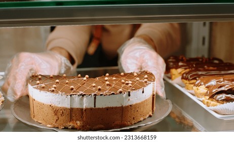 In the bakery cafe closeup to the camera capturing video of a salesman arrange carefully chocolate cake from the showcase fridge