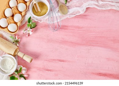 Bakery  Or Cooking Frame With Flowers, Ingredients, Kitchen Items For Pastry On Pink Background,  Spring Cooking Theme. Top View, Copy Space.