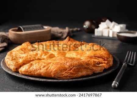 Bakery. Delicious Homemade cheese pie with pastry. Bulgarian banitsa. Traditional Romanian baked house pie with cheese. Close-up of burek pie with cheese stuffing. Greek feta pie on dark background.