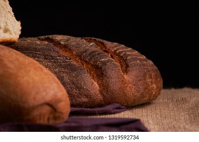Bakery - gold rustic crusty loaves of bread and buns on black chalkboard background. Still life captured from above - Shutterstock ID 1319592734