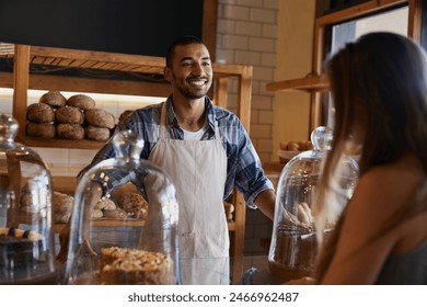 Bakery, happy and man in cafe with customer for serving pastry, cakes and baked foods for small business. Restaurant, coffee shop and waiter or barista by counter for service, help and talk to woman - Powered by Shutterstock