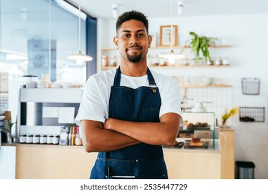 Bakery, happy portrait of hispanic black man in cafe ready for serving pastry, coffee and baked foods. Restaurant, coffee shop and confident waiter barista by counter for service, help and welcome - Powered by Shutterstock