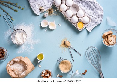 Bakery ingredients - flour, eggs, butter, sugar, yolk, almond nuts on blue table. Sweet pastry baking concept. Flat lay, copy space, top view.