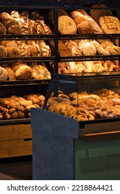 Bakery shop display. Bakery products on shelves and counters. Shelves with different sorts of bread, buns and pretzels. Beautiful shop display of baked products. German modern bakeshop with abundance.