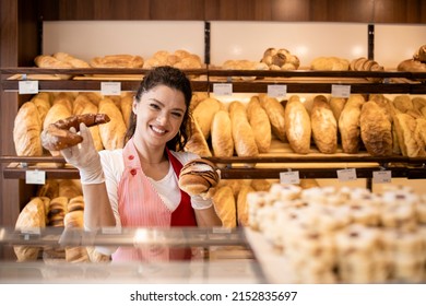 Bakery shop interior and portrait of smiling caucasian female worker in uniform holding pastry for sale. - Powered by Shutterstock