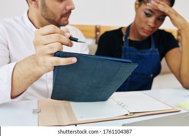 Bakery Shop Owner Discussing Financial Report With Poor Figures With Sad Shop Assistant