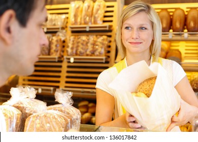 Bakery Shopkeeper Hands Bag Of Bread Over To Customer