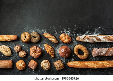 Bakery - Various Kinds Of Breadstuff. Bread Rolls, Baguette, Bagel, Burger Bun And Croissant Captured From Above (top View, Flat Lay). Black Chalkboard Background With Free Copy (text) Space.