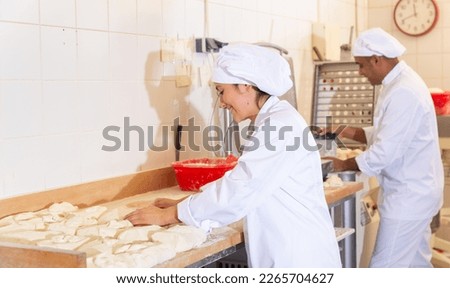 Bakery worker preparing raw dough for baking