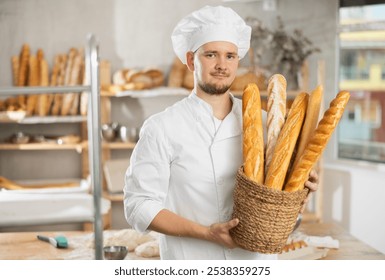 Bakerys advertising banner. Male baker holds basket with finished products, shows many different baguettes. - Powered by Shutterstock