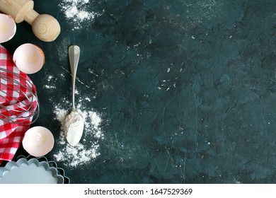 Baking backgeround with rolling pin, eggshell and flour on dark background. Cooking concept. Top view with copy space.