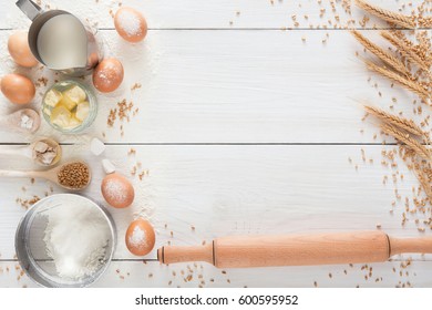 Baking Background. Cooking Ingredients For Yeast Dough And Pastry, Eggs, Flour And Milk On White Rustic Wood. Top View With Copy Space, Mockup For Menu, Recipe Or Culinary Classes.