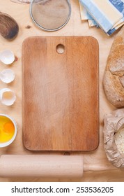 Baking background with cutting board, eggshell, bread, flour, rolling pin. Vintage wood table from above. Rustic background with free text space.