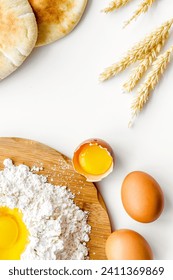 Baking background with eggs, flour and bread on white desk, top view.