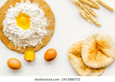 Baking background with eggs, flour and bread on white desk, top view.