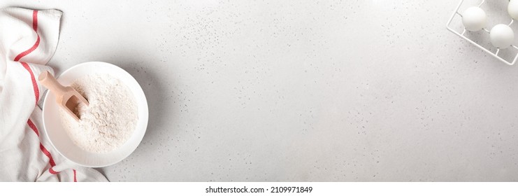 Baking background with flour, eggs, kitchen tools, utensils and cookie molds on white marble table. Top view. Flat lay style. Mock up.