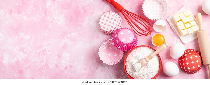 Baking background. Food ingredients for baking flour, eggs, sugar on pink background flat lay. Baking or cooking cakes or muffins. Long format with copy space. Top view