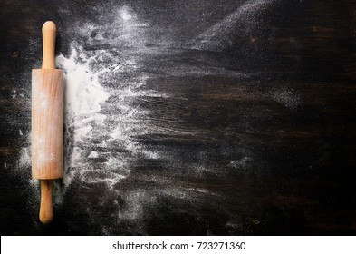 Baking background with free space for your text. Rolling pin and flour on black table. Copy space. Top view
