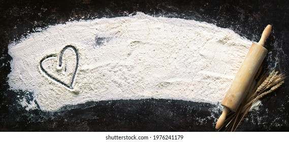 Baking background. Heart of flour and rolling pin on dark table with copy space, top view - Powered by Shutterstock