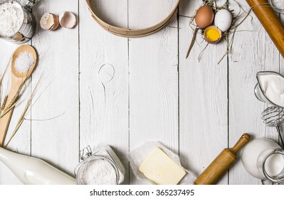 Baking background. Ingredients for the dough - Milk, eggs, flour, sour cream, butter, salt and different tools. On a white wooden background. Free space for text . Top view