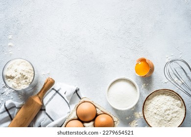 Baking background ingredients. Flour, sugar, eggs and others at light stone table. Top view with copy space.