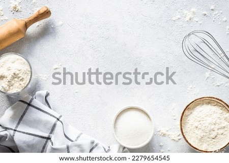 Baking background at light stone table. Flour, sugar, eggs and rolling pin. Top view with copy space.