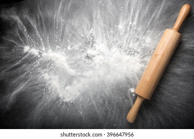Baking background with the rolling pin with flour. On the dark table. Free space for text . Top view