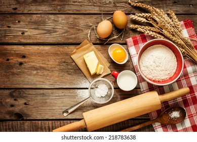 Baking cake in rural kitchen - dough recipe ingredients (eggs, flour, milk, butter, sugar) on vintage wooden table from above. Background layout with free text space. - Powered by Shutterstock