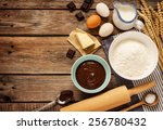 Baking chocolate cake in rural or rustic kitchen. Dough recipe ingredients (eggs, flour, milk, butter, sugar) on vintage wood table from above. Background layout with free text space.