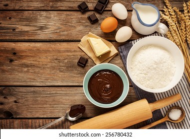 Baking Chocolate Cake In Rural Or Rustic Kitchen. Dough Recipe Ingredients (eggs, Flour, Milk, Butter, Sugar) On Vintage Wood Table From Above. Background Layout With Free Text Space.