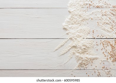 Baking class or recipe concept on white wood background, sprinkled wheat flour and grain with copy space. Top view on wooden table. Cooking dough or pastry.
