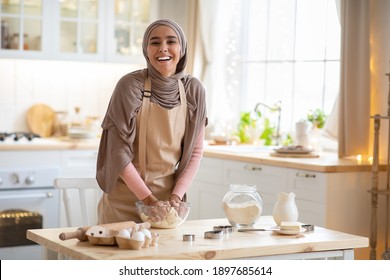 Concepto De Hormigón. Retrato De Una Joven Musulmana Con Hiyab Armando Masa En El Interior De La Cocina, Una Alegre Mujer Islámica Con Hiyab Y Apron Divirtiéndose Mientras Preparaba Pastel Casero, Riéndose De La Cámara