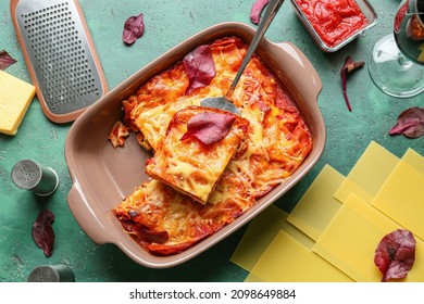 Baking dish with delicious lasagna, tomato sauce and ingredients on color table