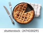 Baking dish with tasty homemade apple pie, napkin and cutlery on blue background