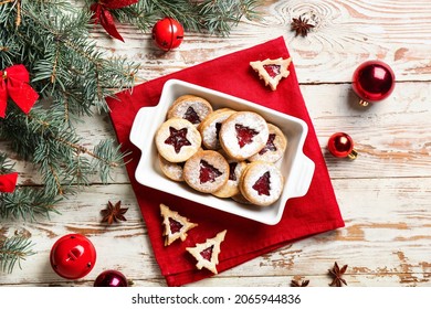 Baking dish with tasty Linzer cookies and Christmas decor on white wooden background