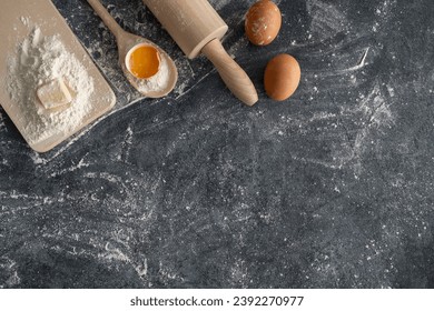 Baking flat lay composition with copy space on a flour-dusted kitchen table. Rolling pin, spoon wooden utensils and fresh dough ingredients - flour, butter, eggs - for a homemade cake. - Powered by Shutterstock - Get 15% off with code: PIKWIZARD15