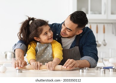 Baking Fun. Happy Arab Dad And Little Daughter Preparing Dough Together In Kitchen, Using Rolling Pin, Cheerful Young Middle Eastern Father And Cute Female Child Cooking At Home, Closeup Shot